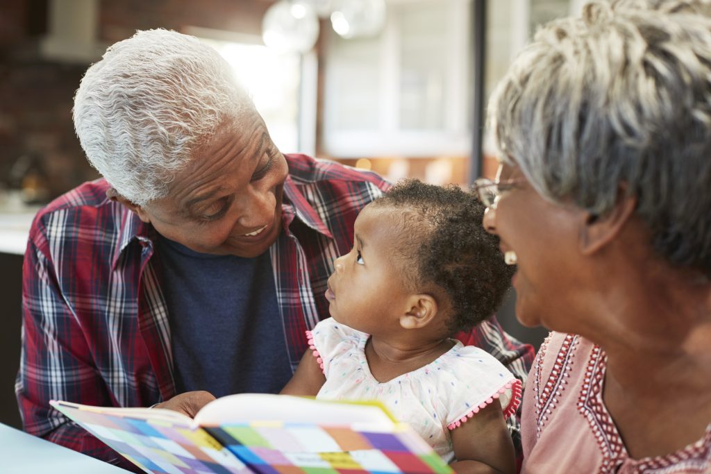 Grandparents Reading Book With Baby Granddaughter