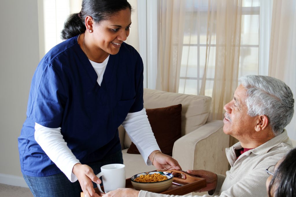 woman caretaker serving elderly gentleman food